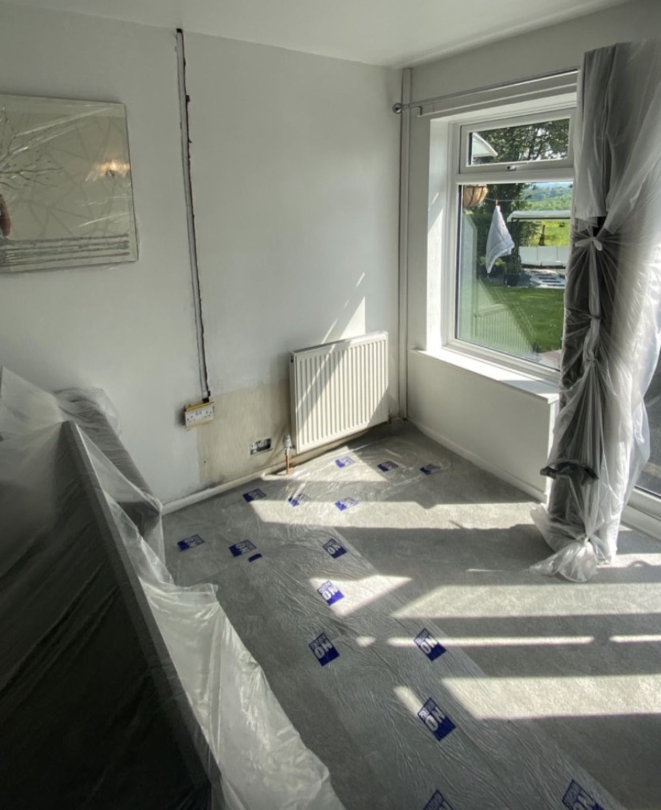 Bedroom cleared of furniture with sockets exposed and belongings covered ready for rewiring